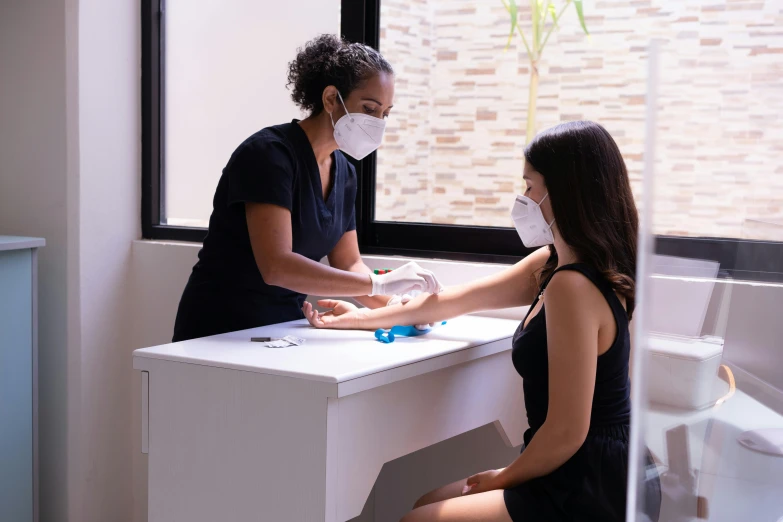 a woman sitting at a desk with a mask on, by david rubín, instagram, palm body, woman holding another woman, as well as scratches, clean medical environment