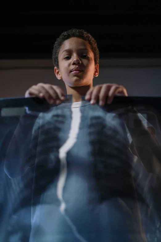 a young man standing in front of an x - ray image, pexels contest winner, hyperrealism, children's, chest coverd, long boi, fujifilm”