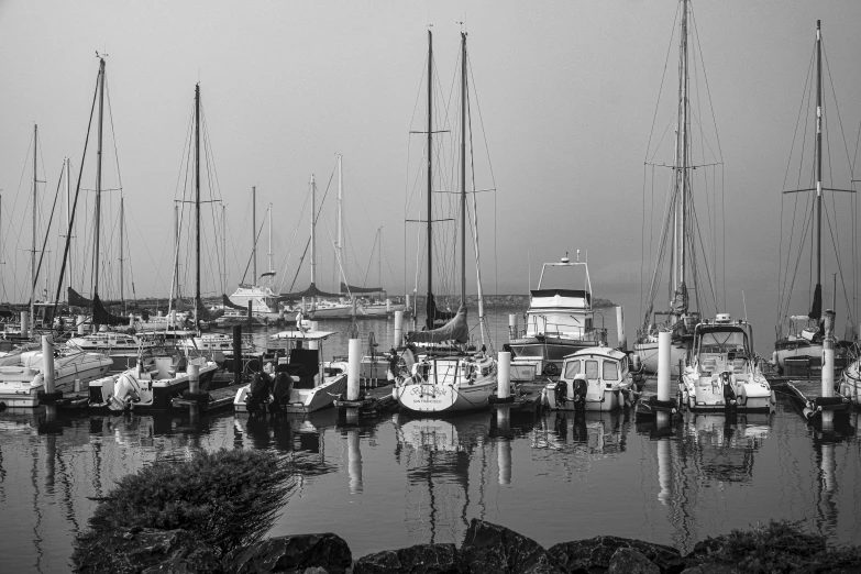 a black and white photo of a marina full of boats, by Dave Melvin, fog. by greg rutkowski, low detailed, sailboat, various posed