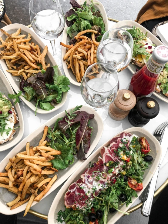 a table topped with lots of different types of food, with fries, thumbnail, tall, exterior shot