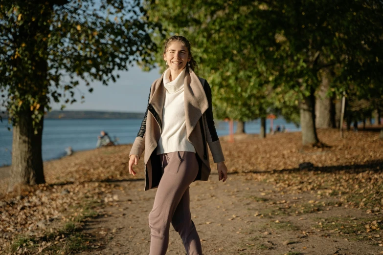 a woman riding a skateboard down a dirt road, a portrait, by Niko Henrichon, pexels, wearing a cardigan, avatar image, autumnal, shoreline