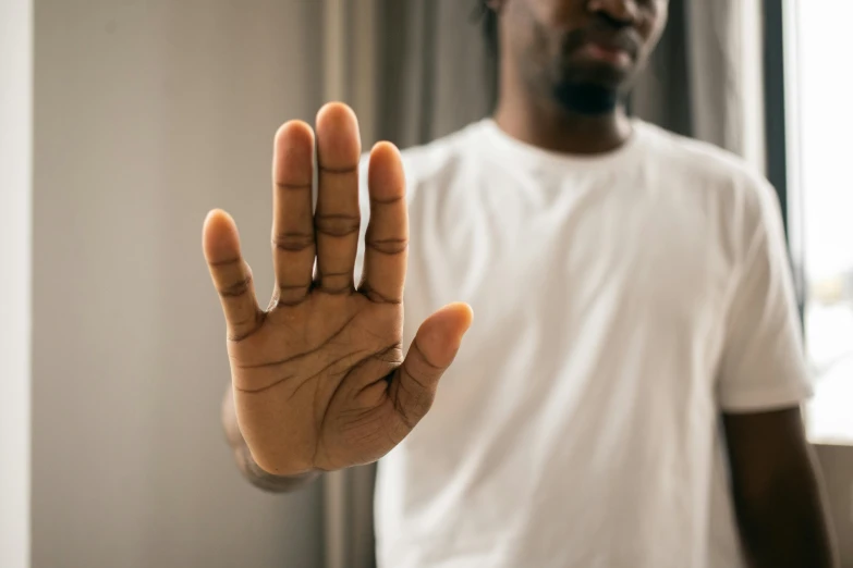 a man standing in front of a window holding his hand up, pexels, man is with black skin, five fingers on the hand, 2 4 - year - old man, hyperdetailled