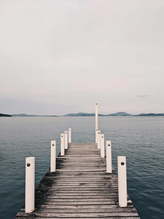 a dock in the middle of a body of water, unsplash, happening, lachlan bailey, slight overcast lighting, pathway, looking across the shoulder