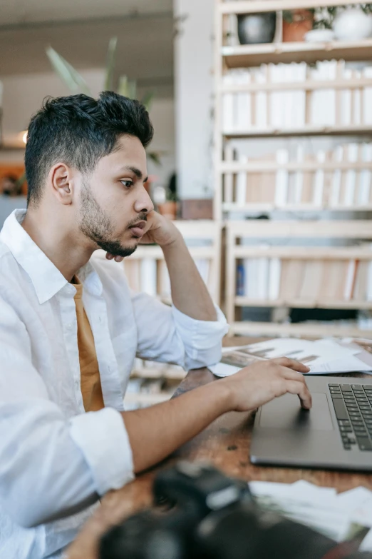 a man sitting in front of a laptop computer, by Adam Rex, trending on pexels, renaissance, looking serious, post graduate, non-binary, wearing a white button up shirt