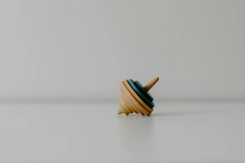 a wooden spinning top on a white surface, unsplash, teal, unicorn horn, ignant, top - side view