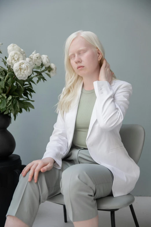 a woman sitting on a chair next to a vase of flowers, inspired by Constantin Hansen, aestheticism, wearing lab coat, intense albino, hands on face, soft aesthetic