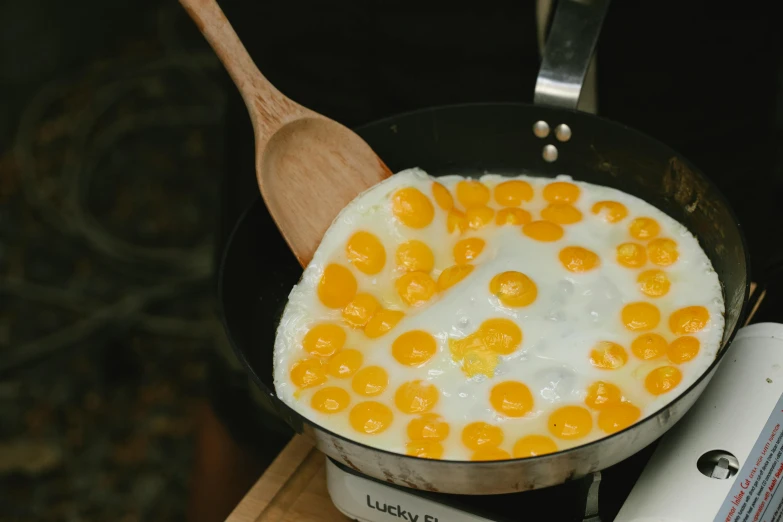 a frying pan filled with eggs on top of a stove, a cartoon, trending on unsplash, hurufiyya, liquid gold, lots of mozzarella balls, thumbnail, woodstock