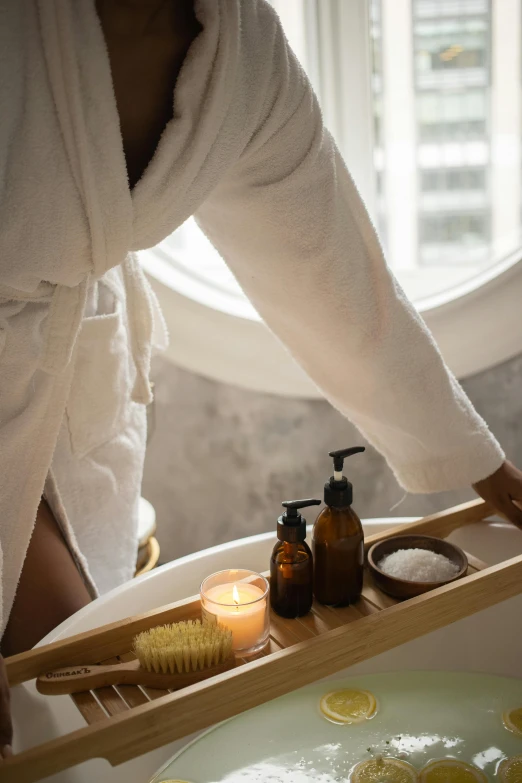 a woman taking a bath in a bathtub, trending on unsplash, renaissance, carrying a bottle of perfume, white candles, dry brushing, wearing a white hospital gown