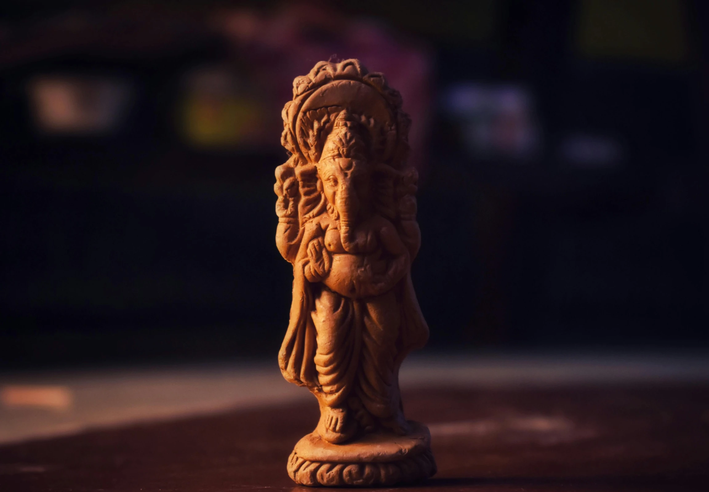 a statue sitting on top of a wooden table, a statue, pexels contest winner, hindu ornaments, clay animation, 33mm photo, holding a wood piece