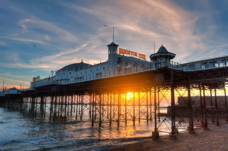 a pier with a sunset in the background, by Tom Bonson, shutterstock, seaside victorian building, 💋 💄 👠 👗, festivals, halfing