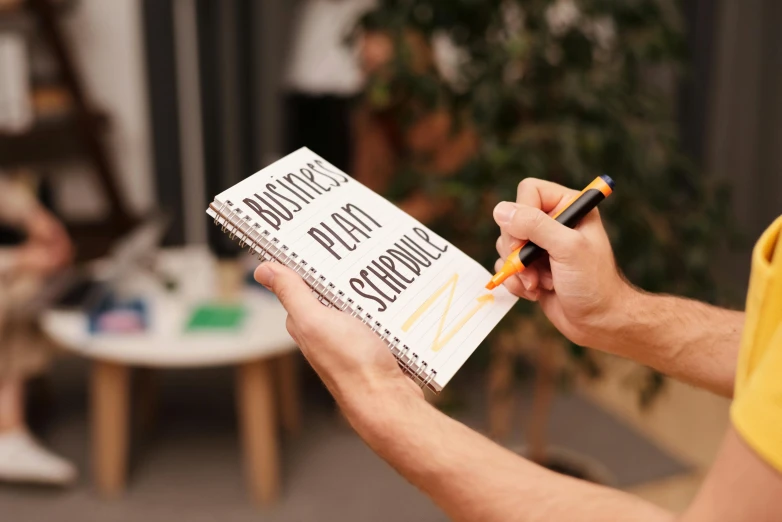 a man holding a notebook with a pen in his hand, by Julia Pishtar, easy to use, with book of science, felt tip pen, demo scene