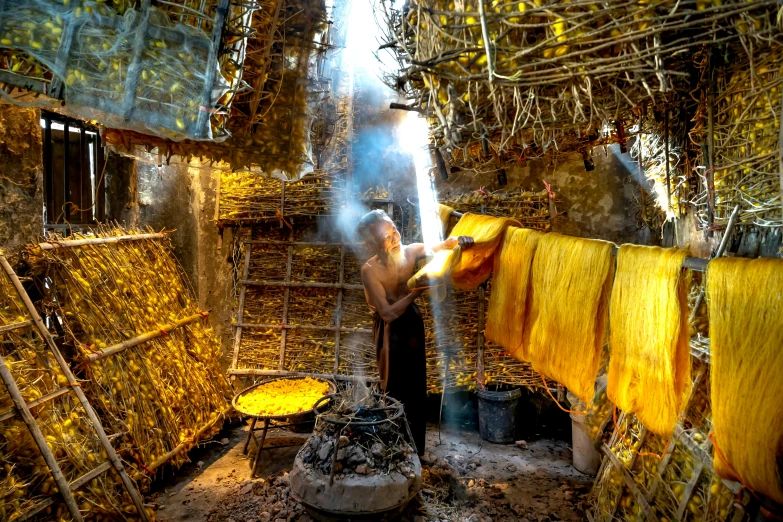 a man that is standing in front of a fire, inspired by Steve McCurry, pexels contest winner, process art, with yellow cloths, in a monestry natural lighting, weaving, praying with tobacco