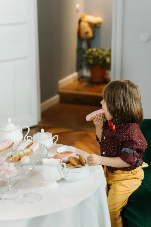 a little girl sitting at a table with a plate of food