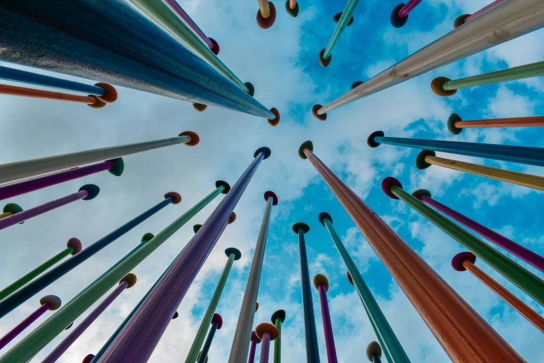 a sky filled with lots of colorful baseball bats, an abstract sculpture, inspired by Bruce Munro, pexels contest winner, kinetic art, pool tubes, tonal colors outdoor, view from the ground, made of glazed