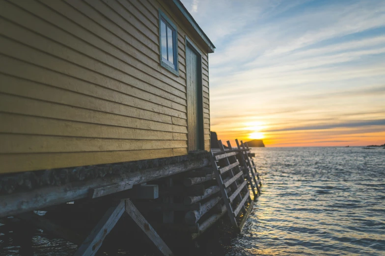 a yellow building sitting on top of a body of water, by Carey Morris, pexels contest winner, wooden cottage, golden hour closeup photo, views to the ocean, inuit heritage