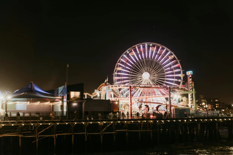 a ferris wheel next to a pier at night, los angeles at night, profile image, fan favorite, neon signs in the distance