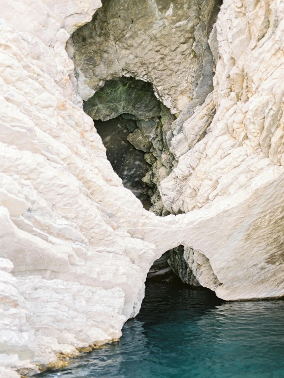 a body of water with a cave in the background, inspired by Nassos Daphnis, unsplash contest winner, romanticism, light cream and white colors, slate, thumbnail, taken with kodak portra