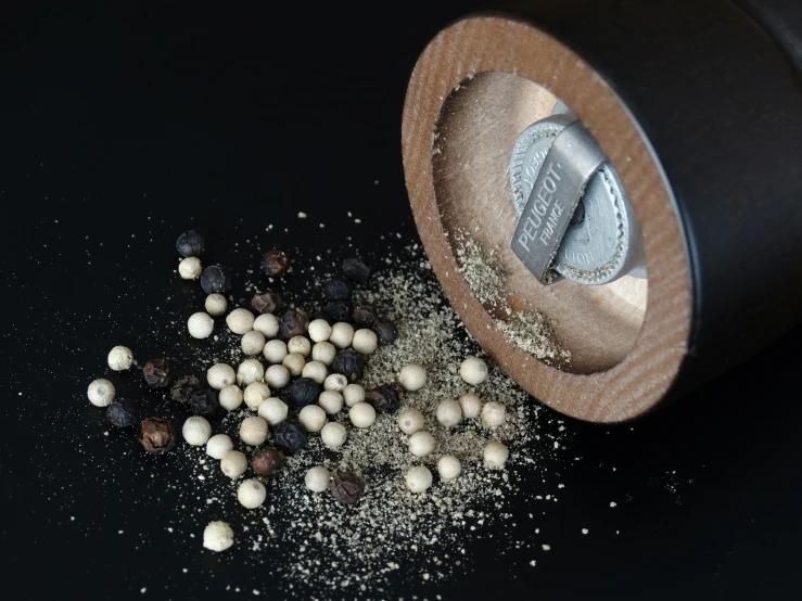 a jar filled with white and black pepper sprinkles, by Paul Davis, pexels contest winner, kinetic pointillism, on textured disc base, bead and reel, a wooden, 3 d metallic ceramic