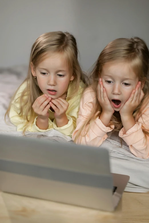 two little girls laying on a bed looking at a laptop, by Matthias Stom, shutterstock, incoherents, live action children's tv show, square, looking surprised, demur