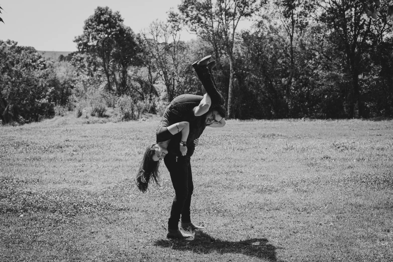 a woman doing a handstand in a field, a black and white photo, unsplash, man and woman in love, goth people dancing, couple kissing, couple