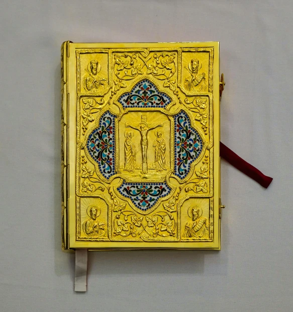 a yellow book sitting on top of a white table, inspired by Carlo Crivelli, unsplash, qajar art, enamel, late 1 9 th century, orthodox, cosplay journal cover