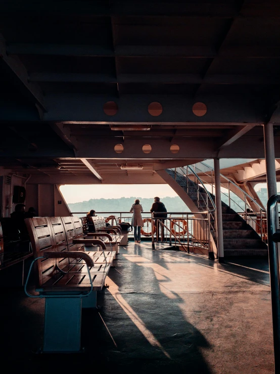 a group of people standing on top of a boat, inspired by Elsa Bleda, pexels contest winner, interior of staten island ferry, walkway, warm lighting with cool shadows, seattle