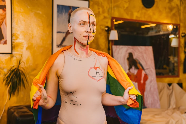 a person in a body suit holding a rainbow flag, a surrealist painting, by Julia Pishtar, pexels contest winner, feminist art, shaved face, on a mannequin. high quality, female anatomy, man with thin lines on the face