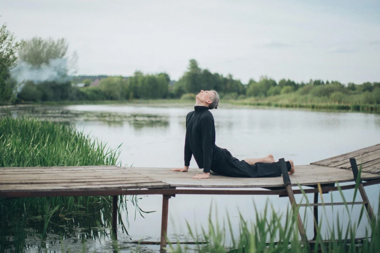 a woman sitting on a dock next to a body of water, by Emma Andijewska, hurufiyya, lying dynamic pose, ukrainian monk, recovering from pain, profile image