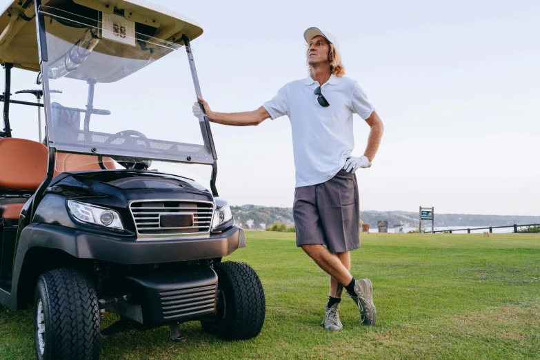 a man standing next to a golf cart, a portrait, by Drew Tucker, unsplash, happening, cargo shorts, he wears dark visors, thumbnail, a long-shot from front