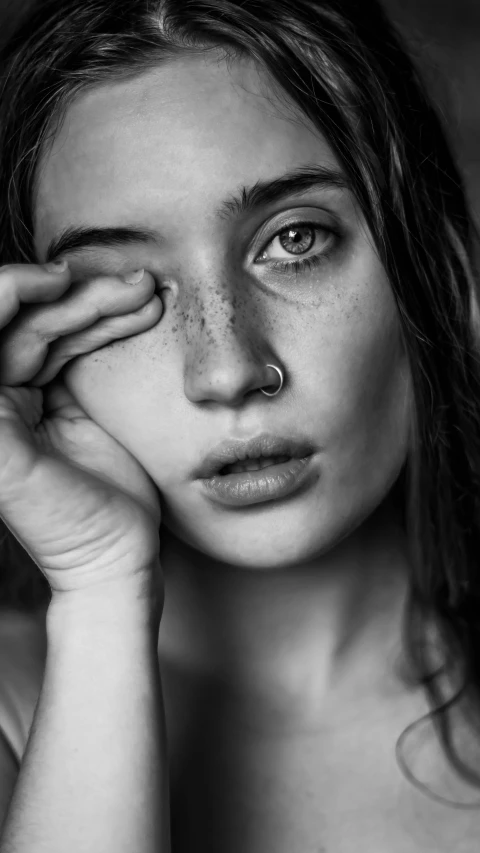 a black and white photo of a woman with freckles, a black and white photo, by irakli nadar, featured on cgsociety, photorealism, portrait sophie mudd, looking tired, nose piercing, close up portrait of a beautiful