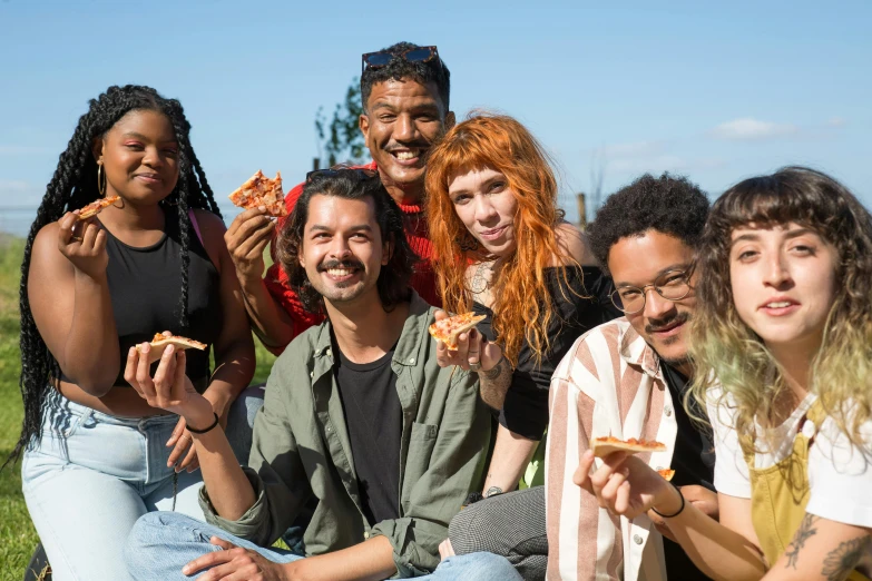 a group of people sitting on top of a grass covered field, a portrait, by Bernie D’Andrea, pexels contest winner, renaissance, holding up a pizza, mixed race, good friends, california;