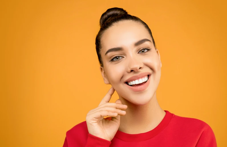 a woman in a red shirt posing for the camera, trending on pexels, antipodeans, yellow uneven teeth, photoshoot for skincare brand, orange color tone, smileing nright