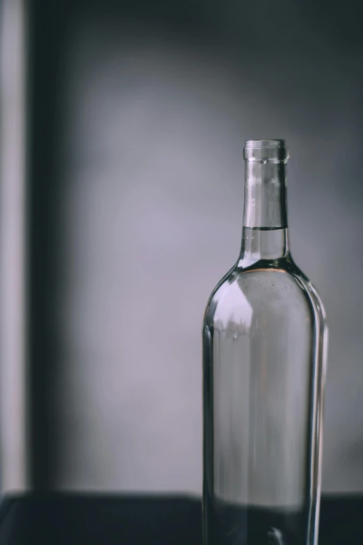 a glass bottle sitting on top of a table, pexels contest winner, renaissance, solid gray, background bar, whites, loosely cropped