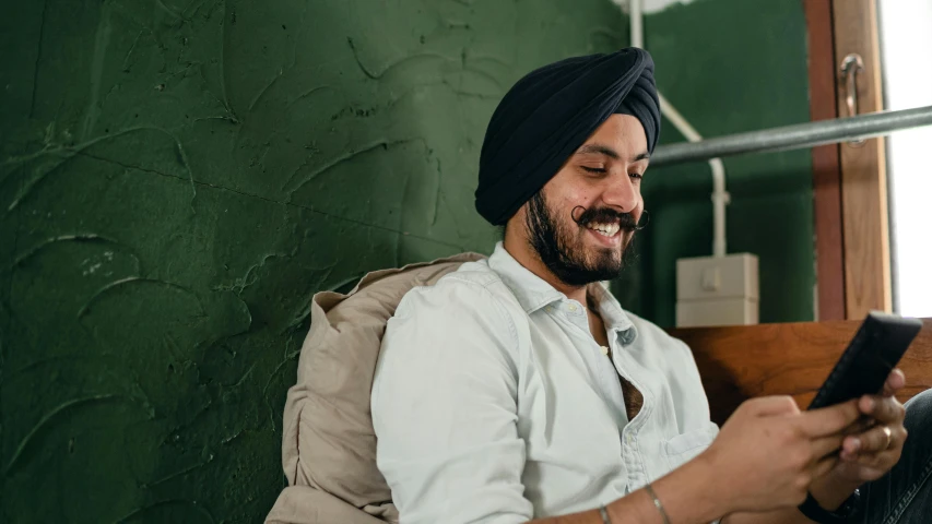 a man sitting on a bed using a cell phone, inspired by Manjit Bawa, trending on pexels, renaissance, head bent back in laughter, sitting in a waiting room, avatar image, close up portrait photo