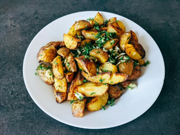 a white plate topped with potatoes on top of a table, by Daniel Lieske, unsplash, fan favorite, frying nails, greek, herbs