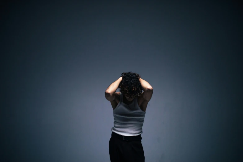 a woman standing in a dark room with her hands on her head, pexels, on a gray background, brutal violence, plain background, ignant