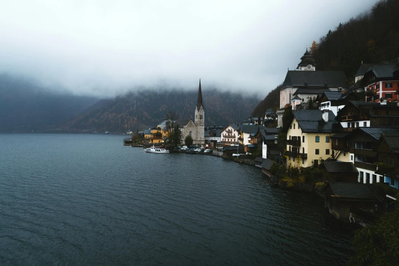 a large body of water next to a small town, by Sebastian Spreng, pexels contest winner, grey mist, alpine architecture, muted colors. ue 5, a quaint