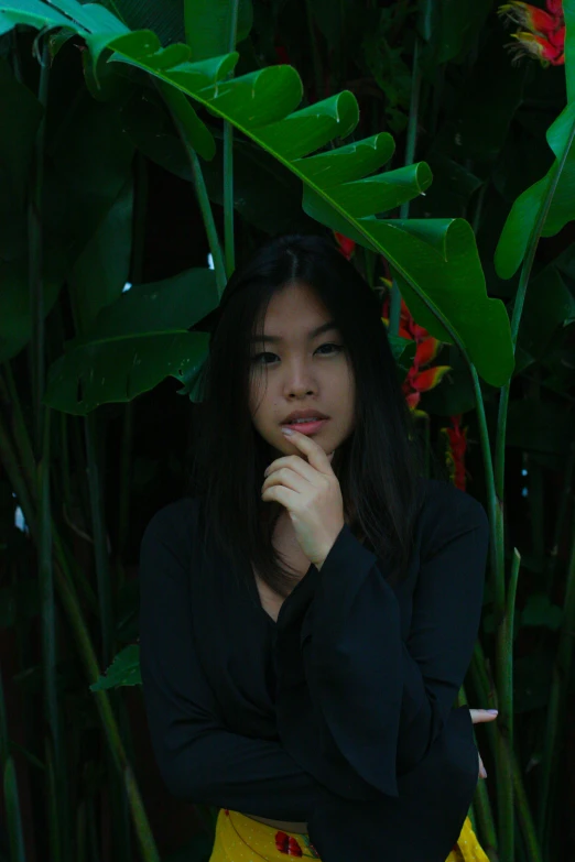 a woman standing in front of a bunch of plants, a picture, inspired by Jung Park, unsplash, sumatraism, wearing a black shirt, ((portrait)), mid - length hair, lily