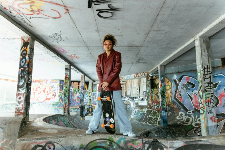 a man standing on top of a skateboard in a skate park, a portrait, by Jakob Gauermann, pexels contest winner, graffiti, in a brown leather maxi jacket, nathalie emmanuel, portrait willow smith, gemmy woud - binendijk