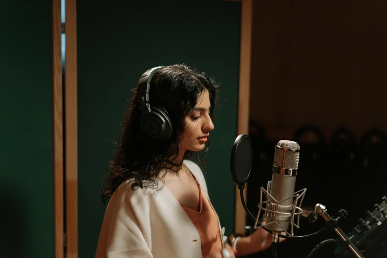 a woman wearing headphones sitting in front of a microphone, an album cover, trending on pexels, studio room, yennefer, behind the scenes photo, candid shot