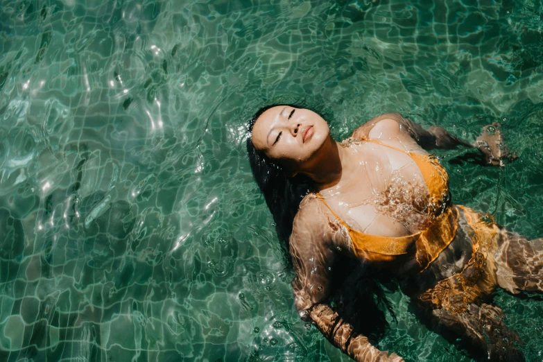 a woman in a yellow bikini laying in the water, inspired by Ren Hang, pexels contest winner, unsplash 4k, beautiful young asian woman, thicc, translucent skin