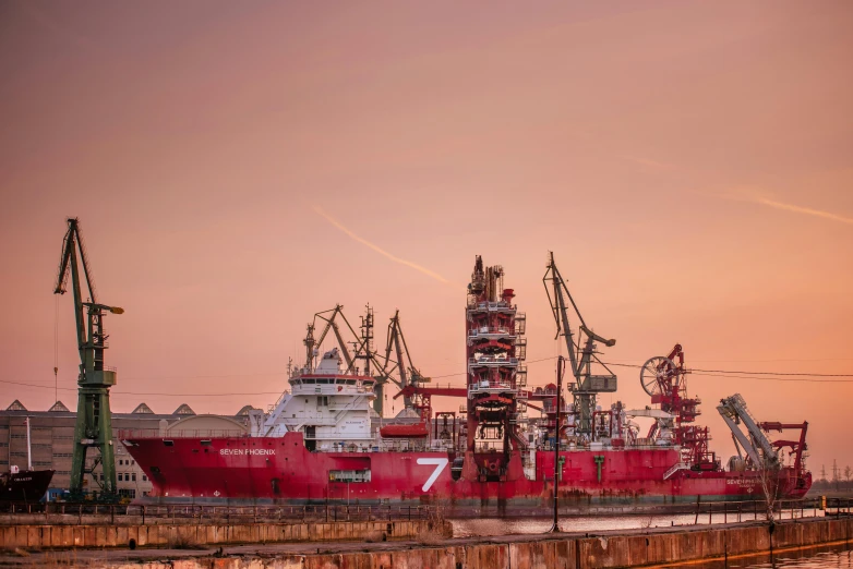 a large red ship sitting on top of a body of water, by Sven Erixson, pexels contest winner, industrial complex, vessels, calm evening, white and red color scheme