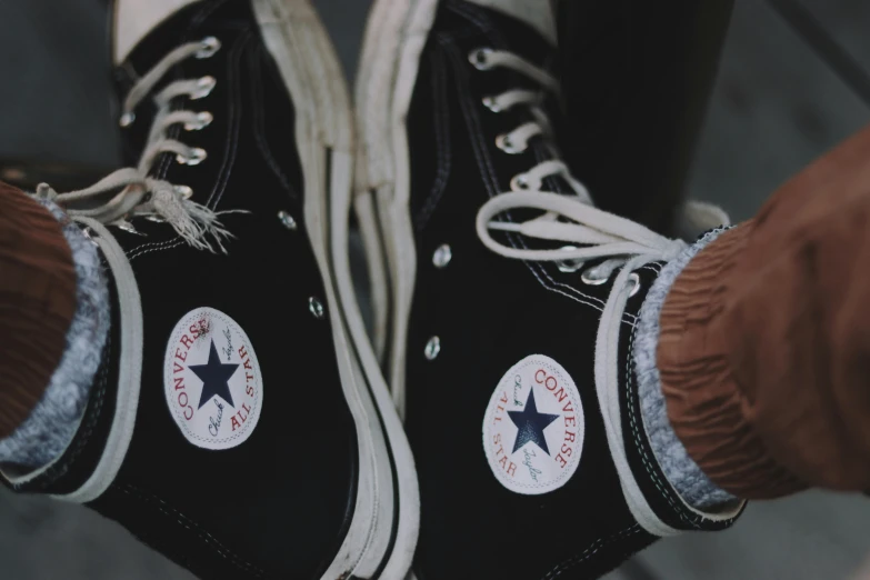 a pair of black converse sneakers with white laces, a photo, trending on pexels, holding a stuff, vintage color, star inside, hoofs