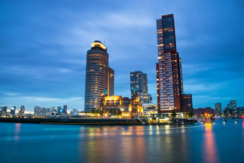 a large body of water next to tall buildings, by Jacob Toorenvliet, pexels contest winner, helmond, skyline showing, evening time, istockphoto