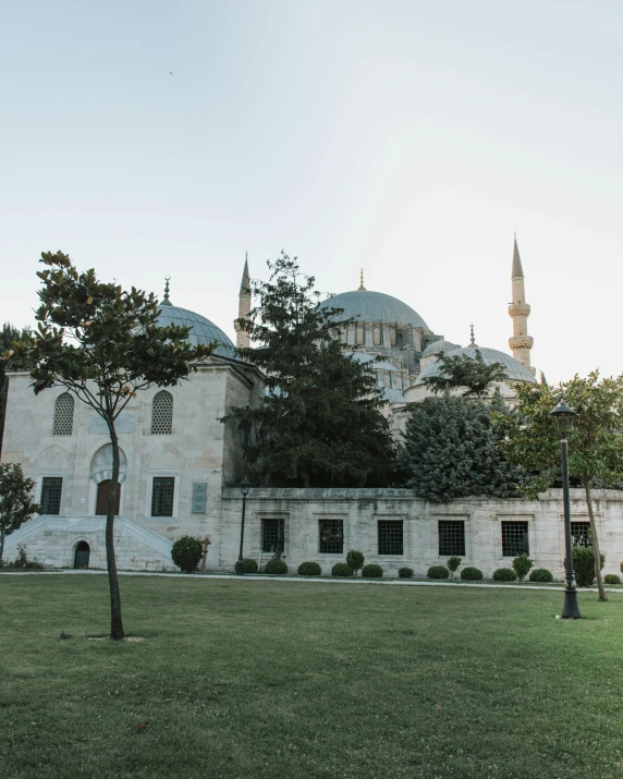 a large white building sitting on top of a lush green field, inspired by Altoon Sultan, pexels contest winner, hurufiyya, with great domes and arches, 🚿🗝📝, a park, istanbul