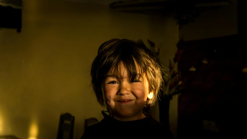 a close up of a child in a dark room, a character portrait, by Maciej Kuciara, pexels contest winner, light smiling, new mexico, sunny lighting, he is very happy