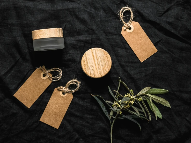 a couple of tags sitting on top of a table, pexels contest winner, skincare, wood and gold details, jars, black jewellery