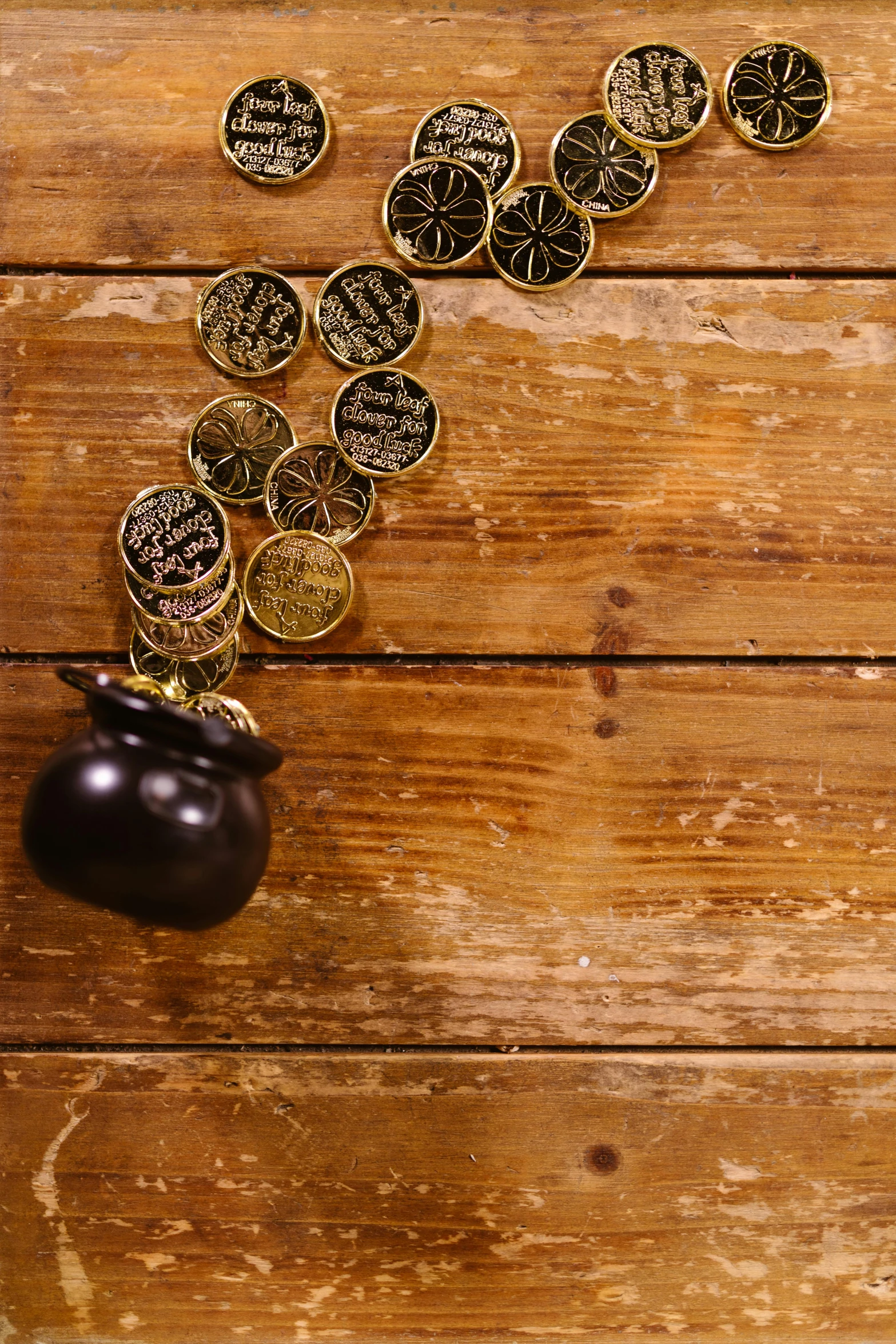 a vase filled with coins sitting on top of a wooden table, black and gold, bells, photograph