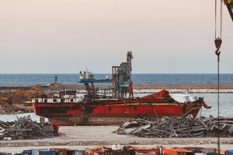 a red boat sitting on top of a beach next to a body of water, pexels contest winner, renaissance, industrial complex, destroyed ship, big graphic seiner ship, red sea