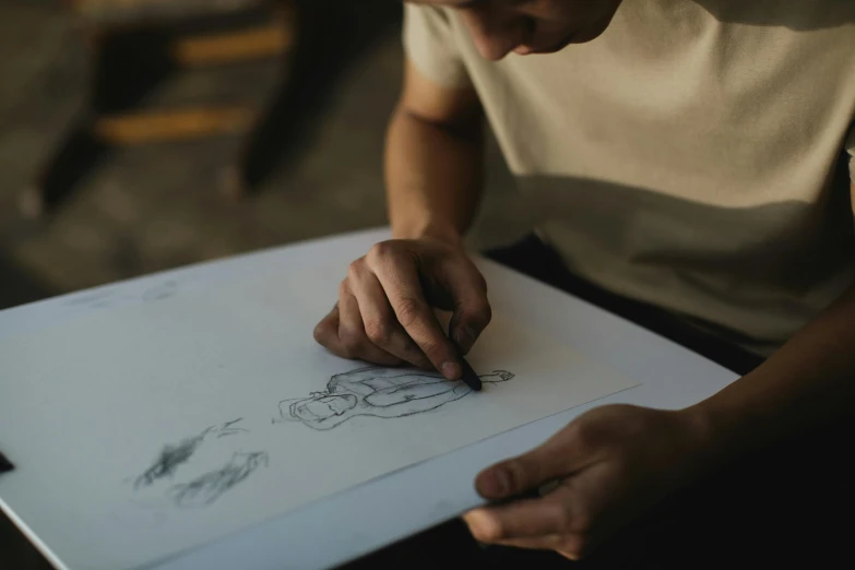 a man is drawing on a piece of paper, a drawing, by Adam Marczyński, pexels contest winner, arbeitsrat für kunst, animation portrait concept art, artisanal art, artistic pose